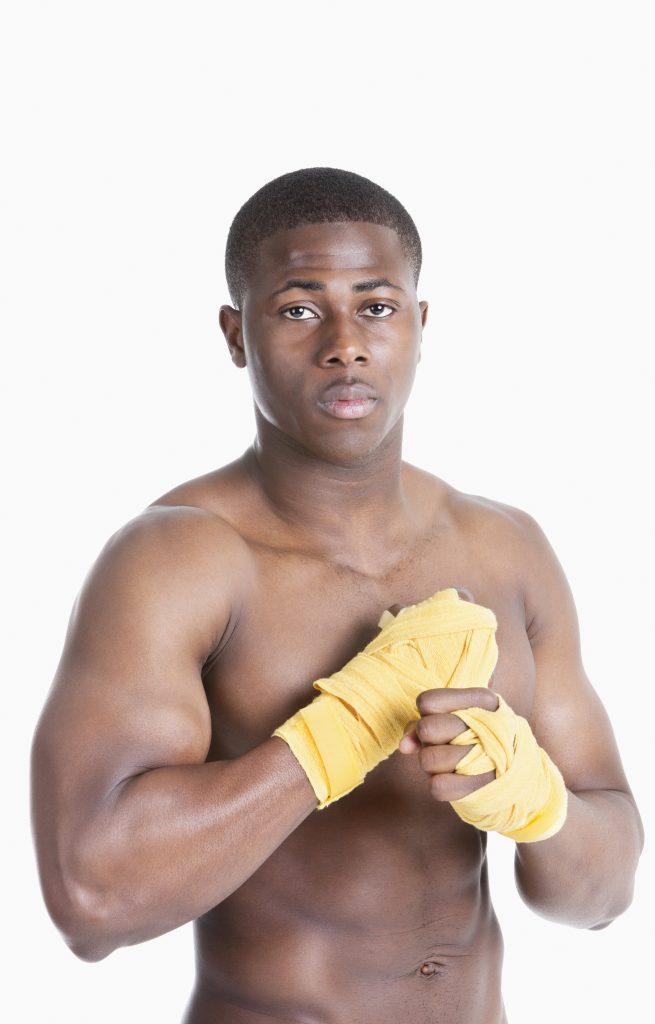 Portrait of a shirtless African American kickboxer over gray background