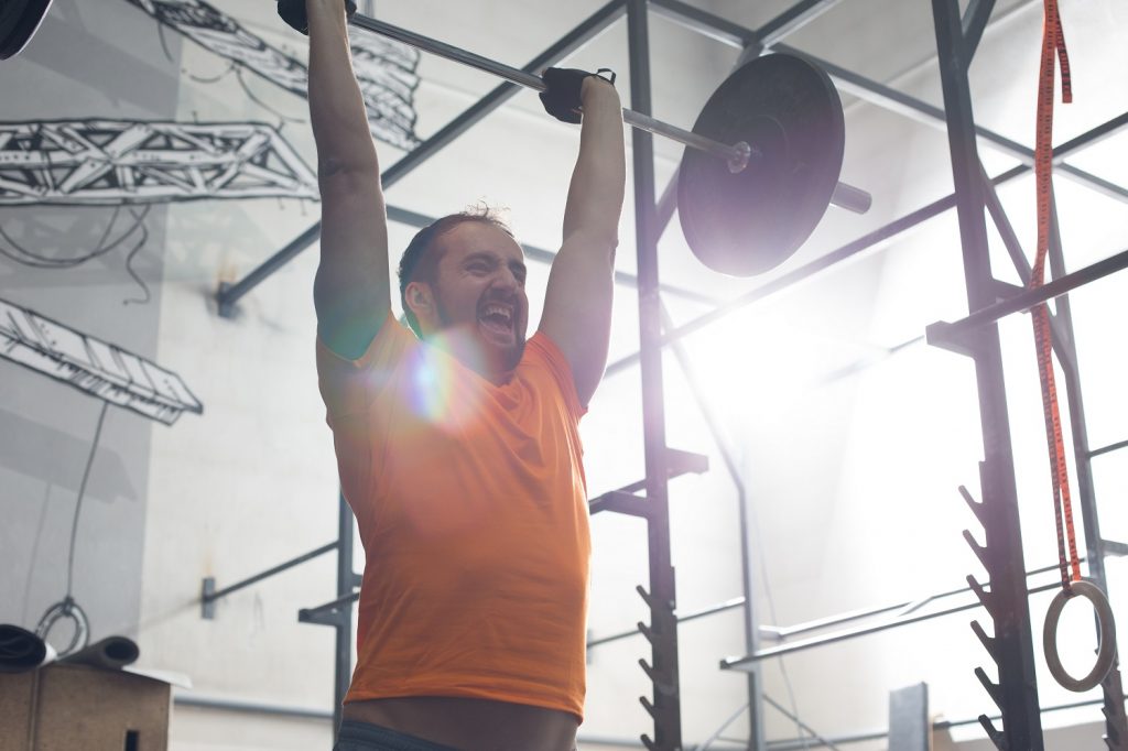 Dedicated man lifting barbell in crossfit gym