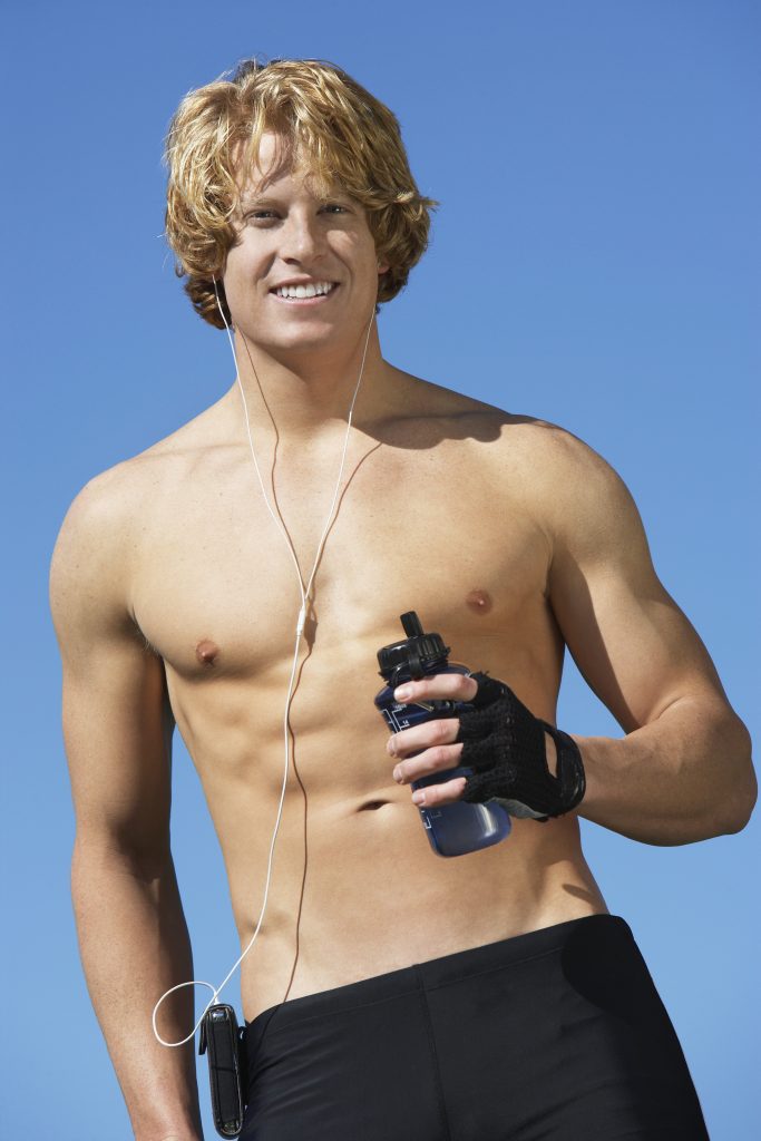 Young man holding water bottle, outdoors, portrait